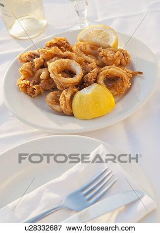 Stock Photo - Greece, Cyclades Islands, Mykonos, Calamari appetizer on set table by sea. Fotosearch
