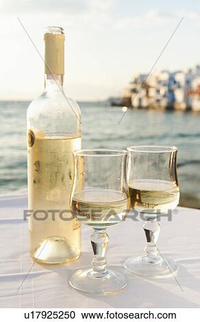 Stock Image - Greece, Cyclades Islands, Mykonos, Wine on table by sea. Fotosearch