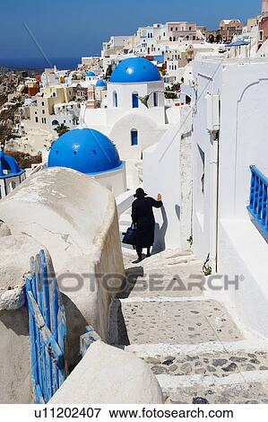 Greece, Cyclades Islands, Santorini, Oia, Woman descending steps past traditional buildings View Large Photo Image Stock Photo - Greece, Cyclades Islands, Santorini, Oia, Woman descending steps past traditional buildings. Fotosearch
