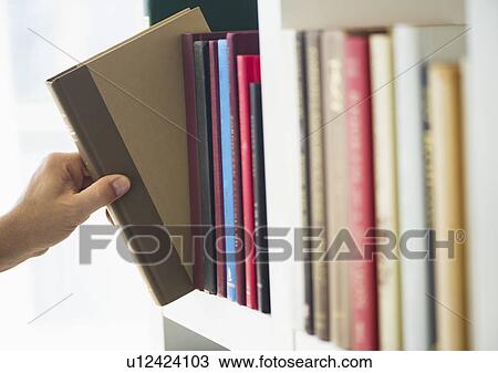 Stock Image - Hand choosing book from shelf. Fotosearch