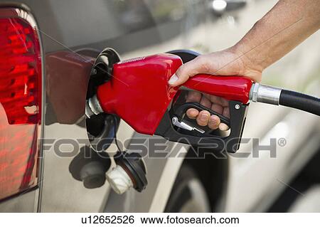 Hand holding fuel pump refueling car View Large Photo Image Stock Photograph - Hand holding fuel pump refueling car. Fotosearch