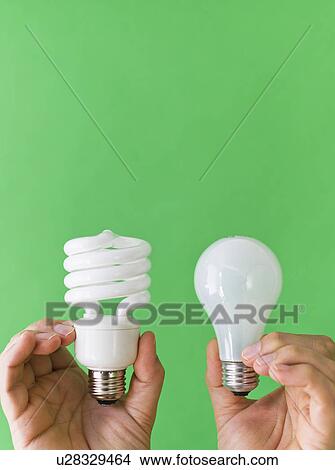 Picture - Hands comparing lightbulbs. Fotosearch