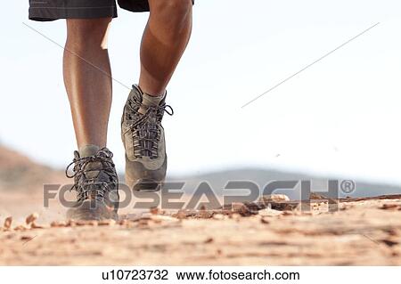 Stock Image - Hiking boots moving across rocky surface. Fotosearch