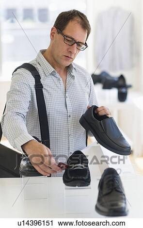 Stock Image - Man choosing shoes in store. Fotosearch