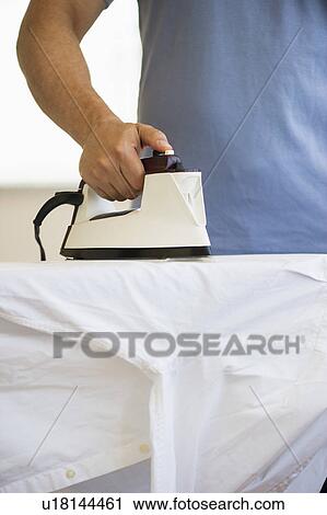 Stock Image - Man ironing shirt. Fotosearch