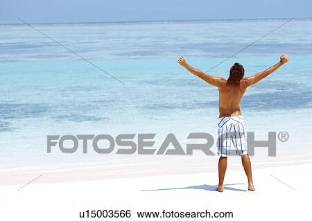 Man standing with his arms wide open on beach View Large Photo Image Stock Photograph - Man standing with his arms wide open on beach. Fotosearch
