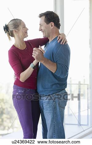 Stock Image - Mature couple dancing in empty living room. Fotosearch