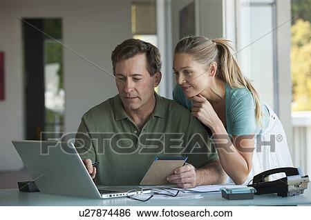 Mature couple working on laptop at home View Large Photo Image Stock Photograph - Mature couple working on laptop at home. Fotosearch