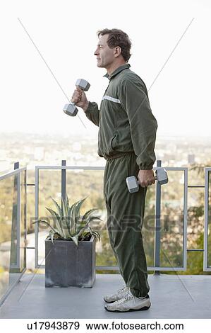Mature man exercising on balcony View Large Photo Image Stock Photo - Mature man exercising on balcony. Fotosearch