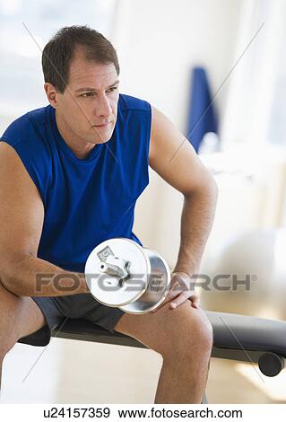Mature man lifting weights in gym View Large Photo Image Stock Photo - Mature man lifting weights in gym. Fotosearch