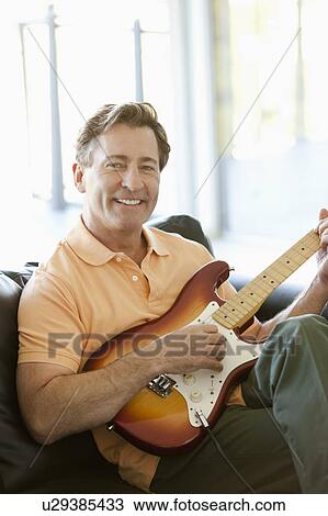 Stock Image - Mature man playing guitar. Fotosearch