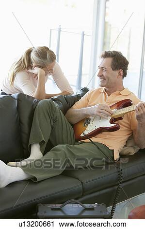 Stock Image - Mature man playing guitar while woman listening. Fotosearch