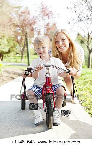 Mother and son (2-3) riding on tricycle in park View Large Photo Image Stock Image - Mother and son (2-3) riding on tricycle in park. Fotosearch