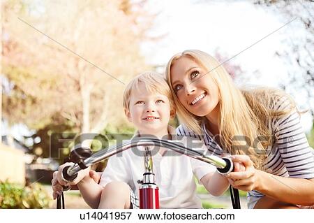 Stock Photo - Mother and son (2-3) riding tricycle in park. Fotosearch