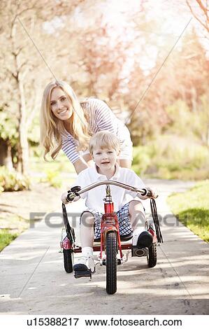 Stock Photo - Mother and son (2-3) riding tricycle in park. Fotosearch