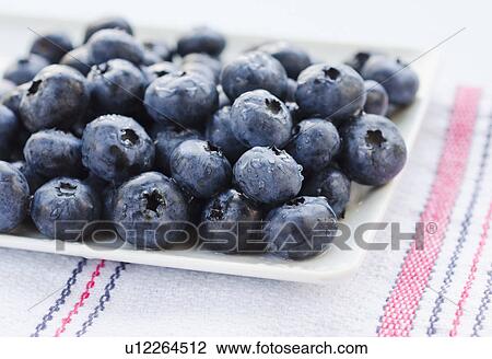 Stock Image - Plate of blueberries on tablecloth. Fotosearch