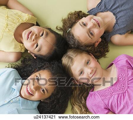 Stock Image - Portrait of girls (6-9) lying on floor. Fotosearch