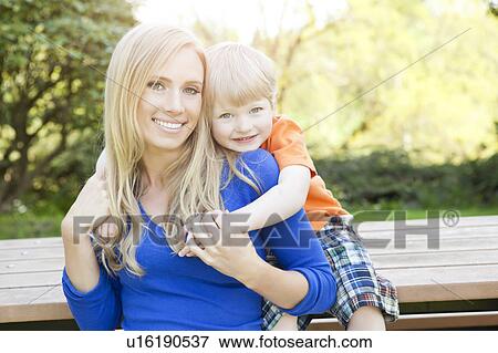 Portrait of mother and son (2-3) sitting at bench in park View Large Photo Image Stock Photo - Portrait of mother and son (2-3) sitting at bench in park. Fotosearch