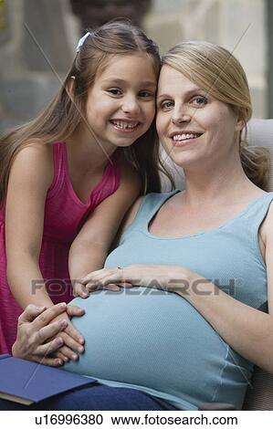 Stock Image - Portrait of pregnant mother with daughter (6-7) . Fotosearch