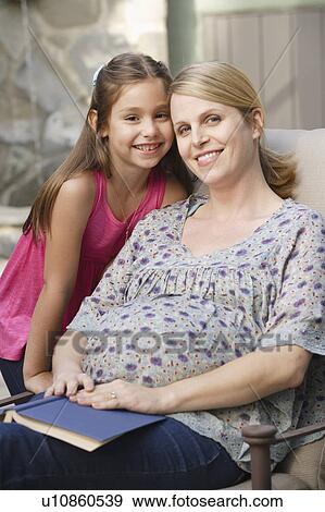 Stock Photo - Portrait of pregnant mother with daughter (6-7) . Fotosearch