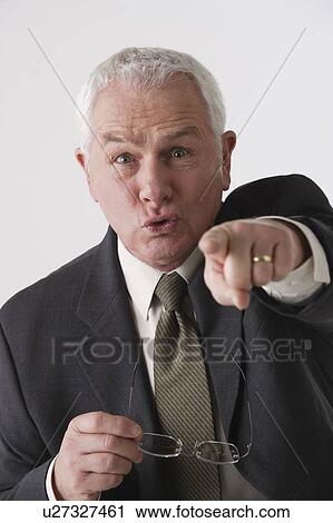 Stock Image - Portrait of senior businessman pointing, studio shot. Fotosearch
