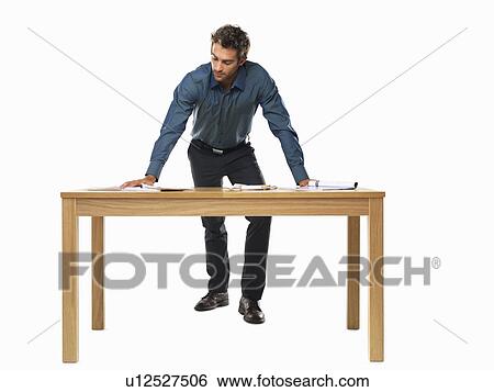 Stock Photograph - Portrait of smart business man standing with palms on table. Fotosearch