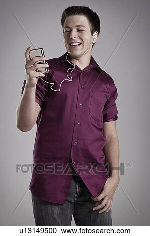 Stock Image - Portrait of smiling teenager listening mp3 player, studio shot. Fotosearch