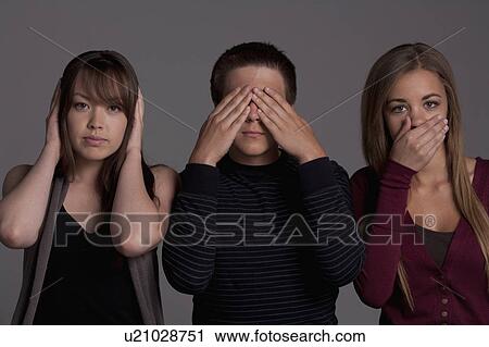 Stock Image - Portrait of teenage boy (16-17) and girl (16-17) with young friend, studio shot. Fotosearch