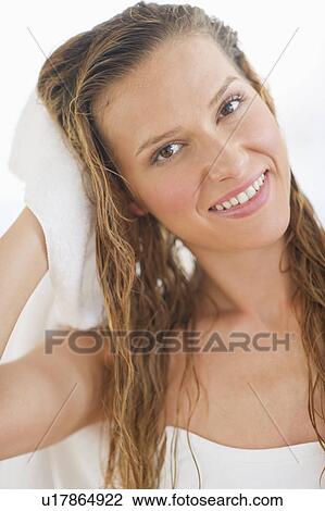 Stock Image - Portrait of woman drying hair. Fotosearch