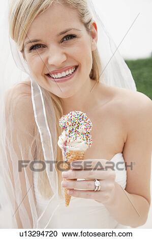 Stock Image - Portrait of young bride eating ice cream. Fotosearch