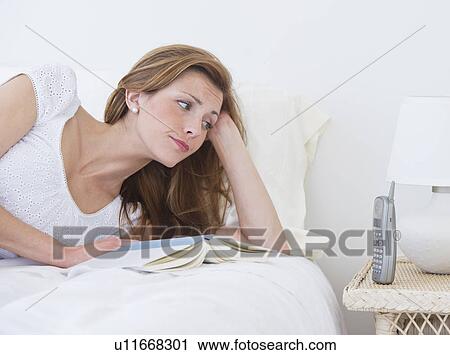 Portrait of young lying on bed and looking at phone View Large Photo Image Stock Image - Portrait of young lying on bed and looking at phone. Fotosearch