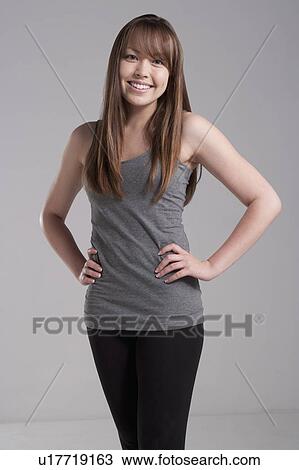 Stock Image - Portrait of young smiling woman, studio shot. Fotosearch