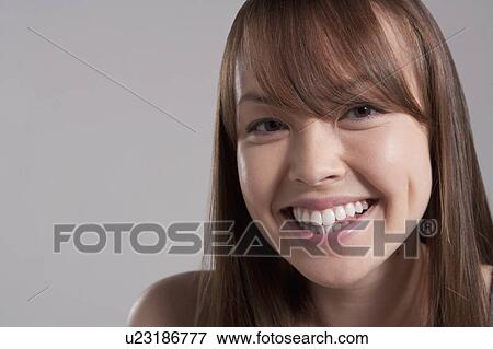 Stock Photo - Portrait of young smiling woman, studio shot. Fotosearch