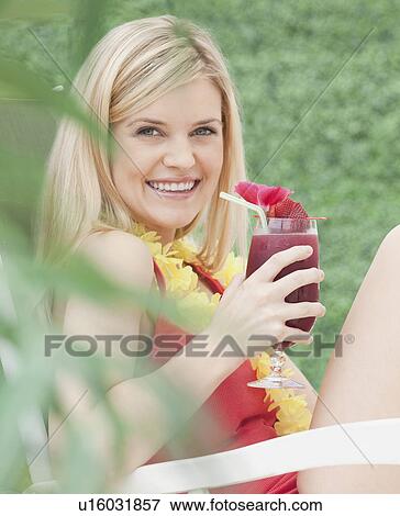 Stock Photo - Portrait of young woman drinking cocktail. Fotosearch
