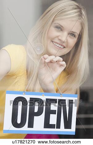 Portrait of young woman hanging sign in window View Large Photo Image Stock Image - Portrait of young woman hanging sign in window. Fotosearch