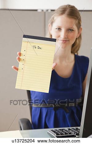 Picture - Portrait of young woman in office with blank list. Fotosearch