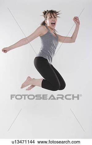 Portrait of young woman jumping, studio shot View Large Photo Image Picture - Portrait of young woman jumping, studio shot. Fotosearch
