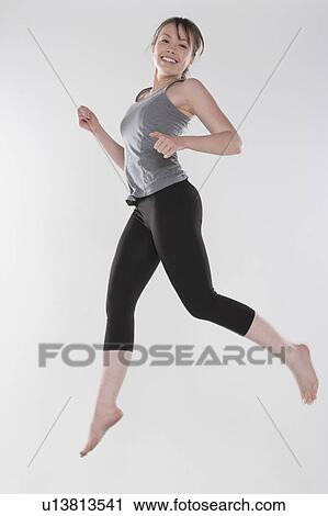 Portrait of young woman jumping, studio shot View Large Photo Image Stock Image - Portrait of young woman jumping, studio shot. Fotosearch
