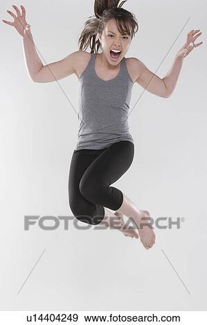 Portrait of young woman jumping, studio shot View Large Photo Image Stock Photo - Portrait of young woman jumping, studio shot. Fotosearch