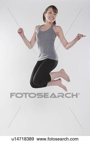 Stock Photo - Portrait of young woman jumping, studio shot. Fotosearch