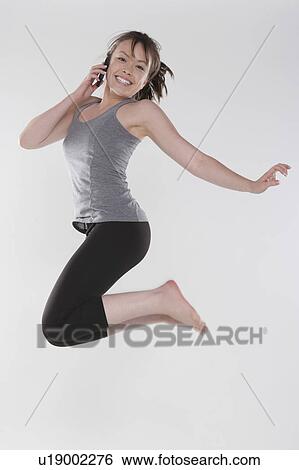 Stock Photograph - Portrait of young woman jumping, studio shot. Fotosearch