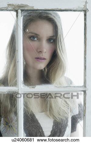 Portrait of young woman looking through window View Large Photo Image Stock Image - Portrait of young woman looking through window. Fotosearch