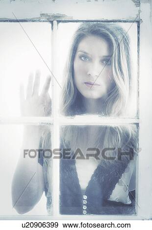 Portrait of young woman looking through window View Large Photo Image Stock Photo - Portrait of young woman looking through window. Fotosearch