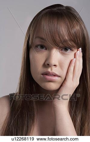 Stock Photo - Portrait of young woman with tooth ache, studio shot. Fotosearch