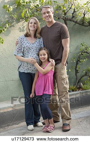 Stock Image - Pregnant mother, father and daughter (6-7) posing for portrait. Fotosearch