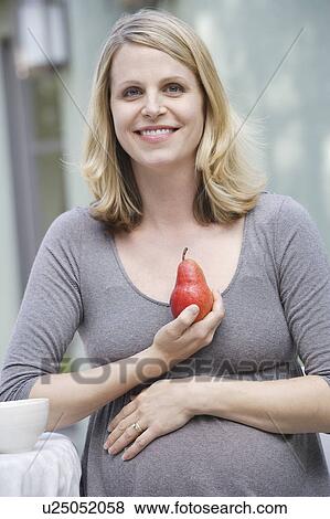 Pregnant woman holding pear View Large Photo Image Stock Photo - Pregnant woman holding pear. Fotosearch