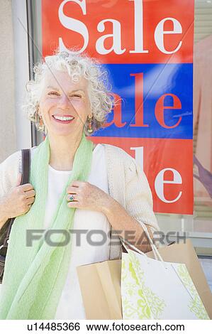 Senior woman standing in front of window display View Large Photo Image Stock Photograph - Senior woman standing in front of window display. Fotosearch