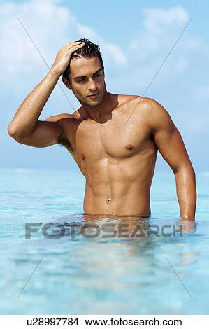 Smart young guy taking a bath in the ocean View Large Photo Image Picture - Smart young guy taking a bath in the ocean. Fotosearch