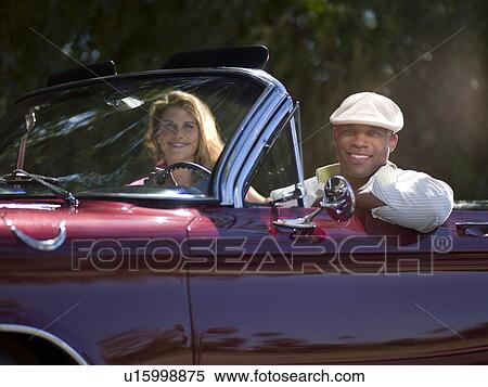 Stock Photography - Smiling couple driving classic's car. Fotosearch