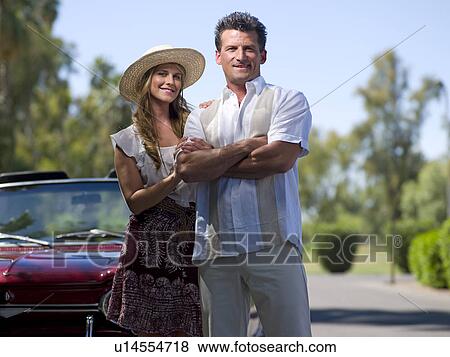 Smiling couple standing near convertible car View Large Photo Image Stock Photo - Smiling couple standing near convertible car. Fotosearch